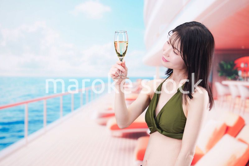 クルーズ船で水着を着てスパークリングワインを飲む若い女性