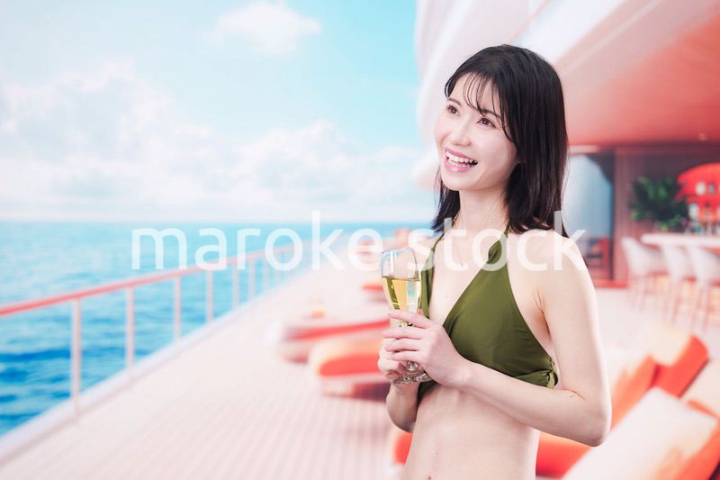 クルーズ船で水着を着てスパークリングワインを飲む若い女性