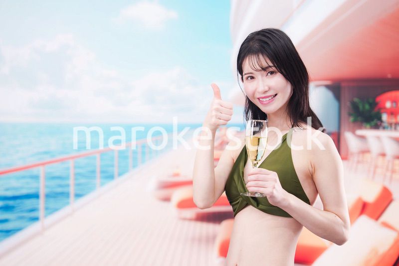 クルーズ船で水着を着てスパークリングワインを飲む若い女性