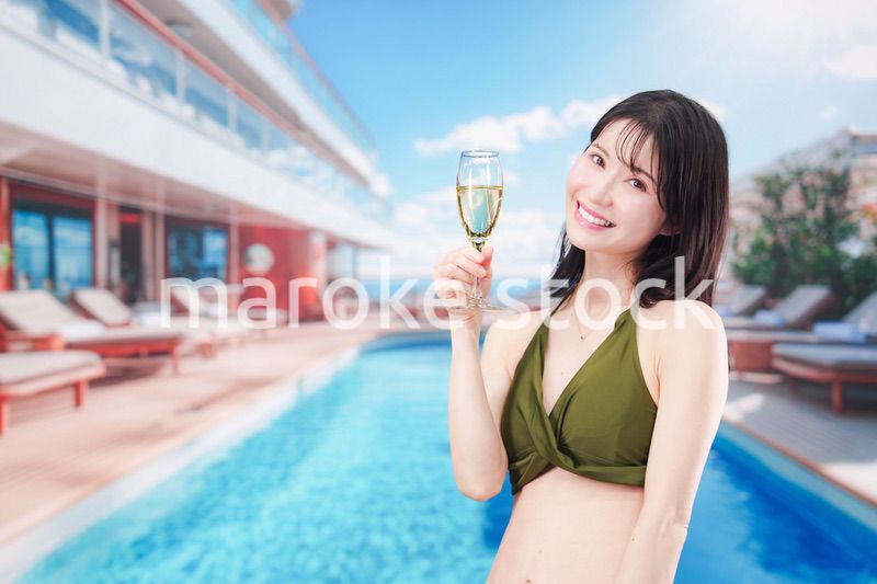 リゾートのプールで水着を着てスパークリングワインを飲む若い女性