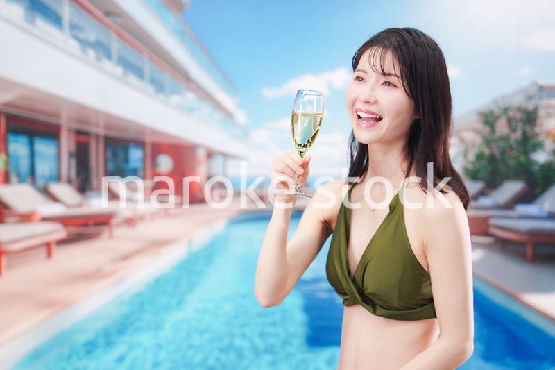 リゾートのプールで水着を着てスパークリングワインを飲む若い女性