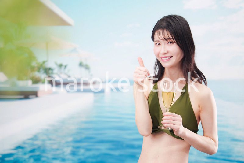 リゾートのプールで水着を着てスパークリングワインを飲む若い女性