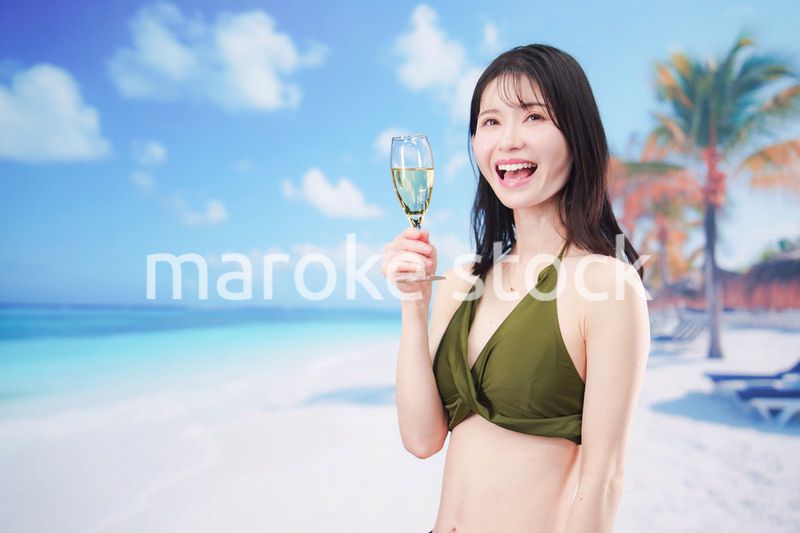 真夏のビーチでスパークリングワインを飲む水着を着た若い女性