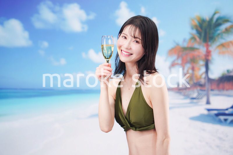 真夏のビーチでスパークリングワインを飲む水着を着た若い女性