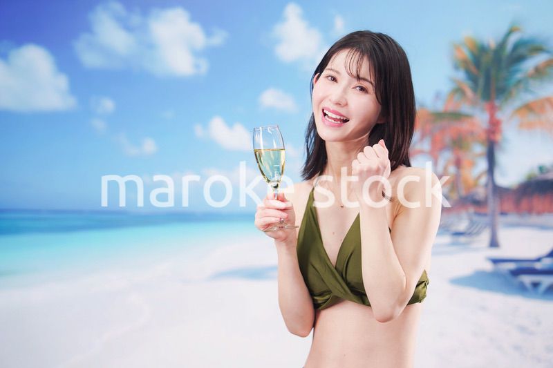 真夏のビーチでスパークリングワインを飲む水着を着た若い女性