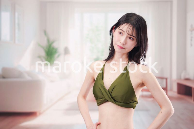 家で水着を試着して体型を気にする若い女性