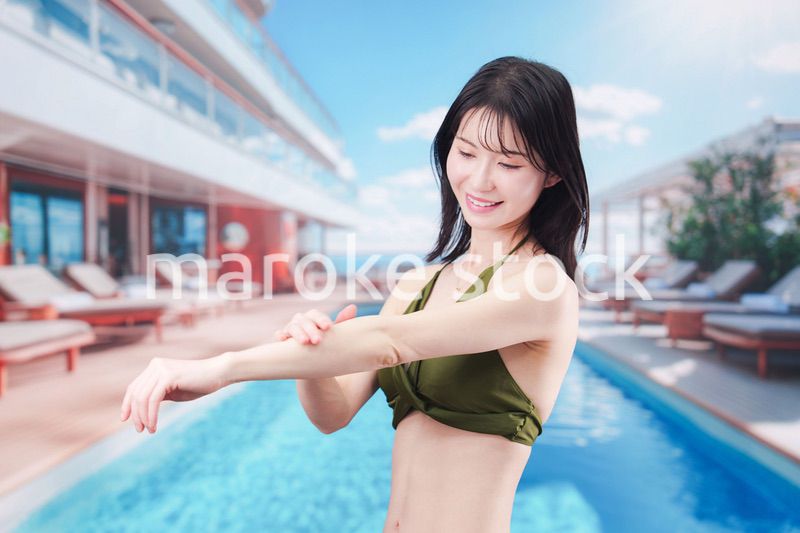 真夏のリゾートで日焼け止めクリームを塗る若い女性