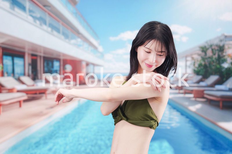 真夏のリゾートで日焼け止めクリームを塗る若い女性