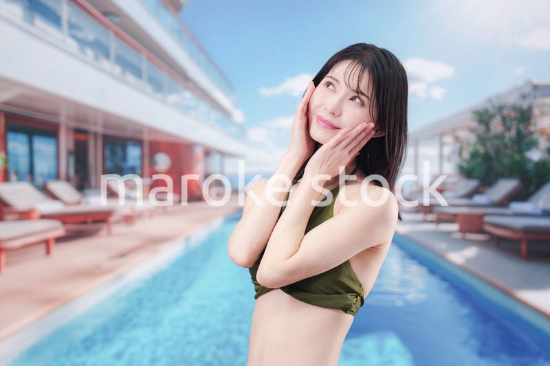 太陽が降り注ぐリゾートで顔に日焼け止めを塗る水着姿の女性