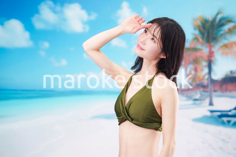 青空のビーチで水着を着た若い女性