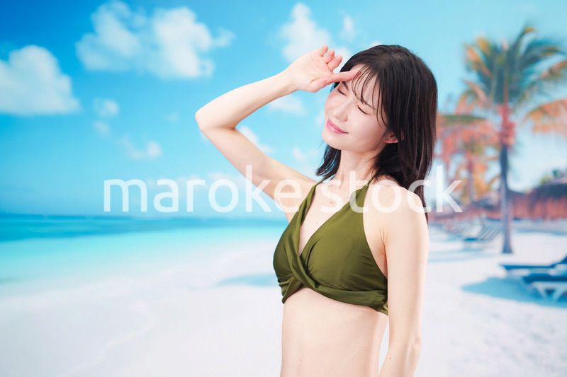 青空のビーチで水着を着た若い女性