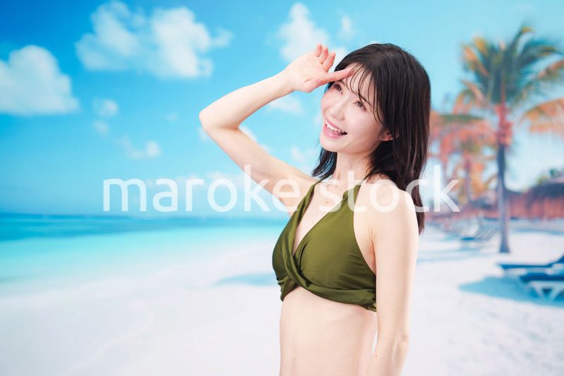 青空のビーチで水着を着た若い女性