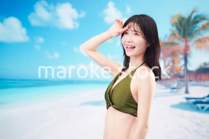 青空のビーチで水着を着た若い女性