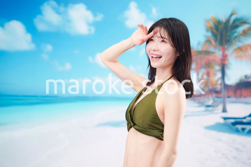 青空のビーチで水着を着た若い女性