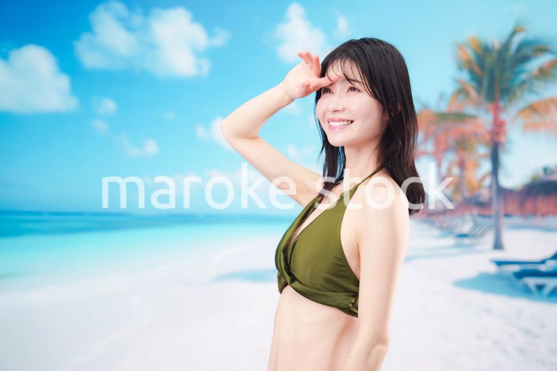 青空のビーチで水着を着た若い女性