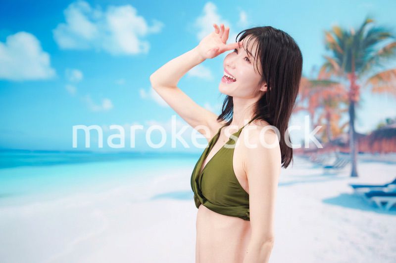 青空のビーチで水着を着た若い女性