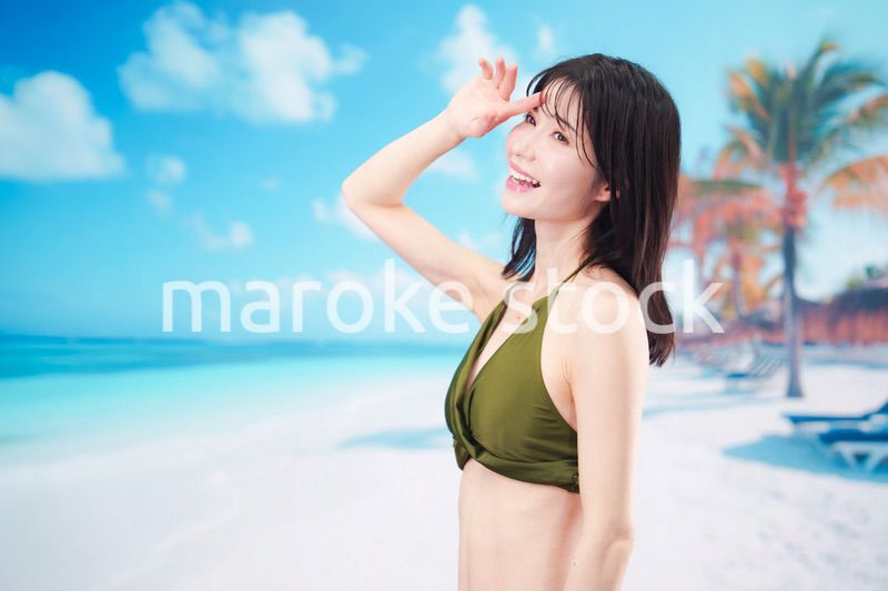 青空のビーチで水着を着た若い女性