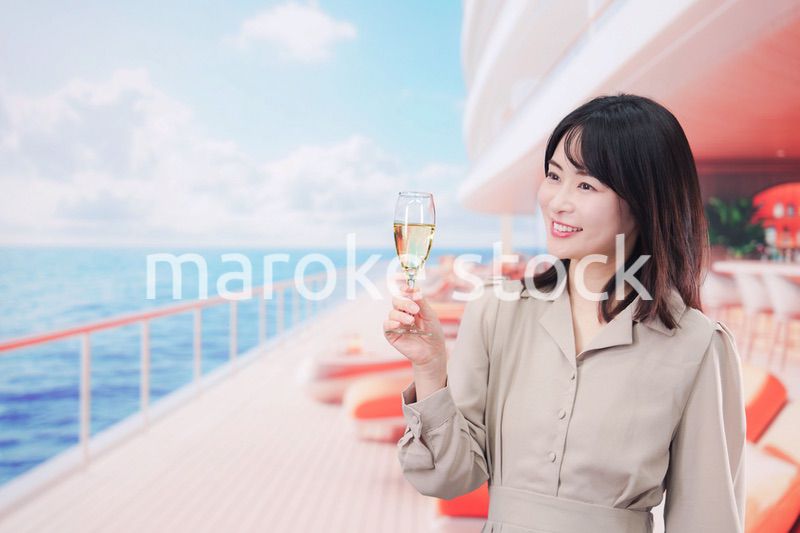 クルーズ船のデッキでスパークリングワインを飲む若い女性