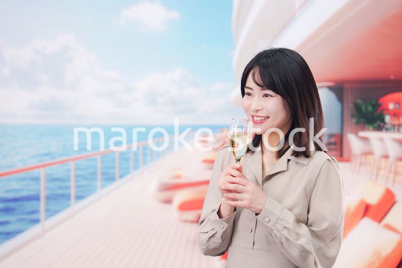 クルーズ船のデッキでスパークリングワインを飲む若い女性