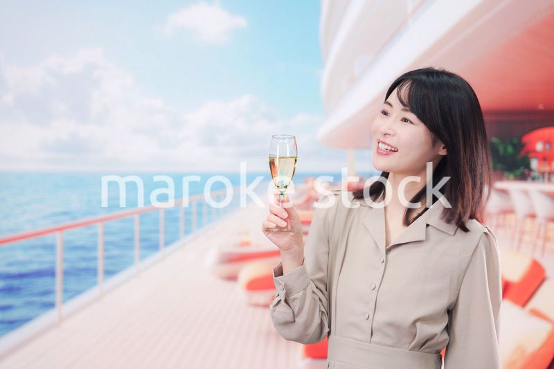 クルーズ船のデッキでスパークリングワインを飲む若い女性