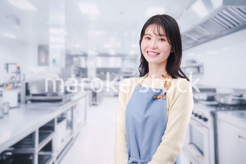 大きな厨房でエプロンを着る若い女性シェフ