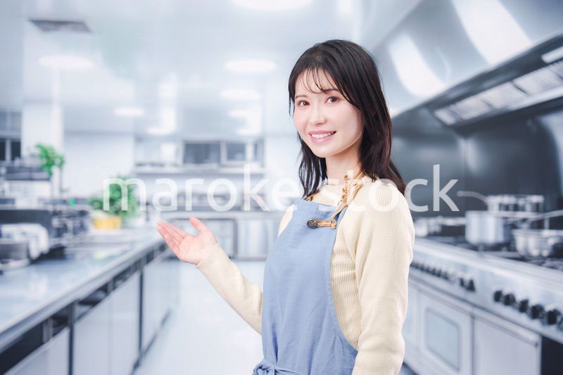大きな厨房でエプロンを着る若い女性シェフ