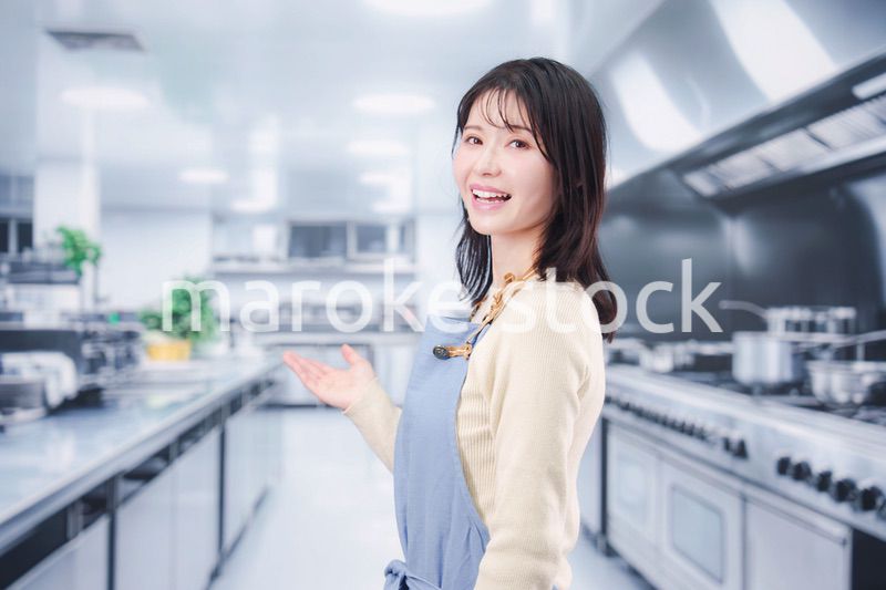 大きな厨房でエプロンを着る若い女性シェフ