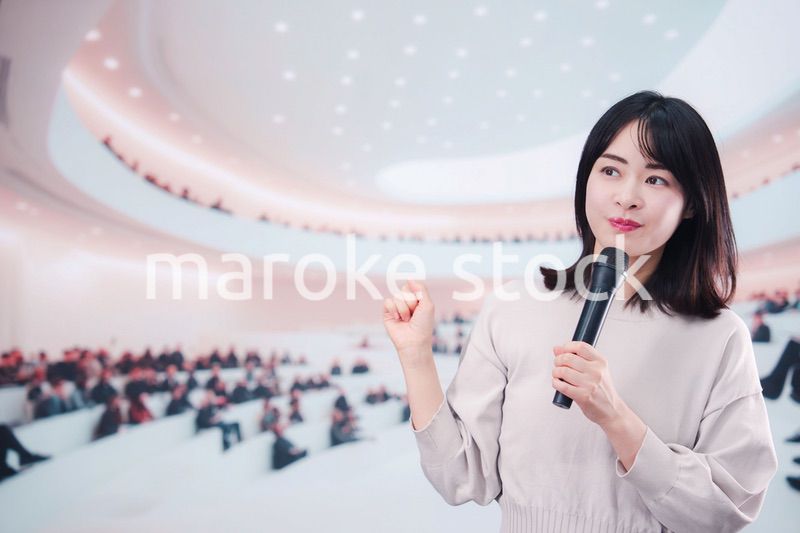 大勢の聴衆の前でマイクで話す女性