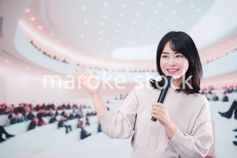 大勢の聴衆の前でマイクで話す女性