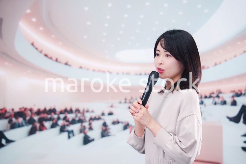 大勢の聴衆の前でマイクで話す女性