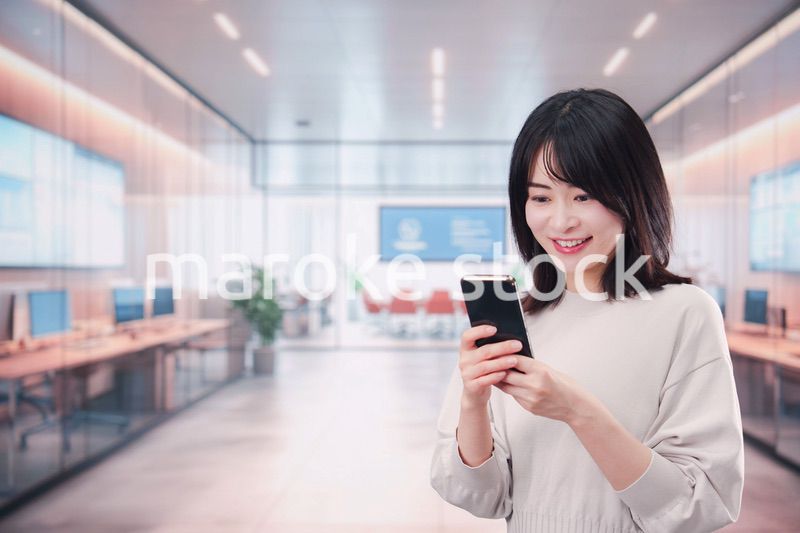 明るいオフィスでスマホを使う若い女性