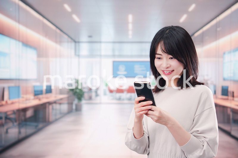 明るいオフィスでスマホを使う若い女性