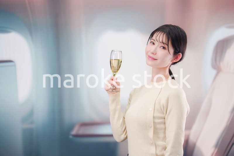 飛行機のビジネスクラスでワインを飲む女性