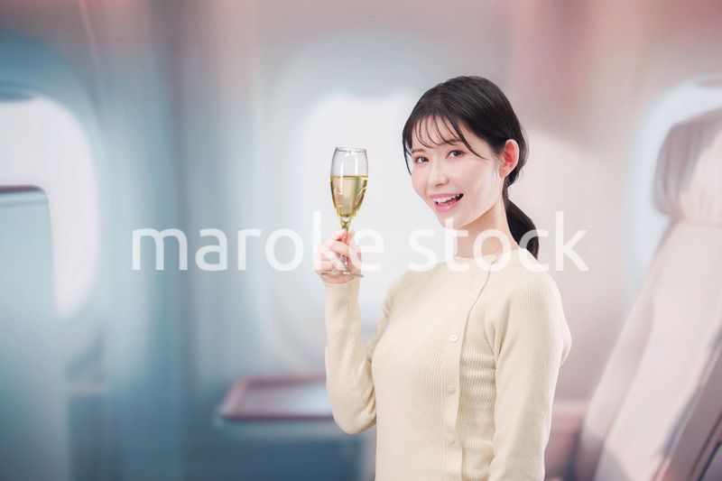 飛行機のビジネスクラスでワインを飲む女性