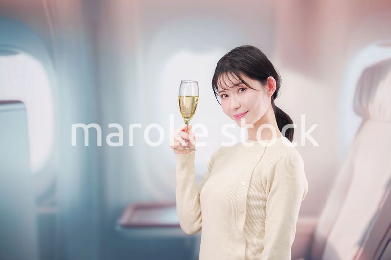 飛行機のビジネスクラスでワインを飲む女性