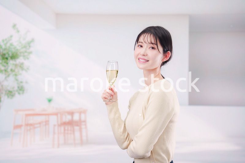 家でグラスワインを飲む若い女性