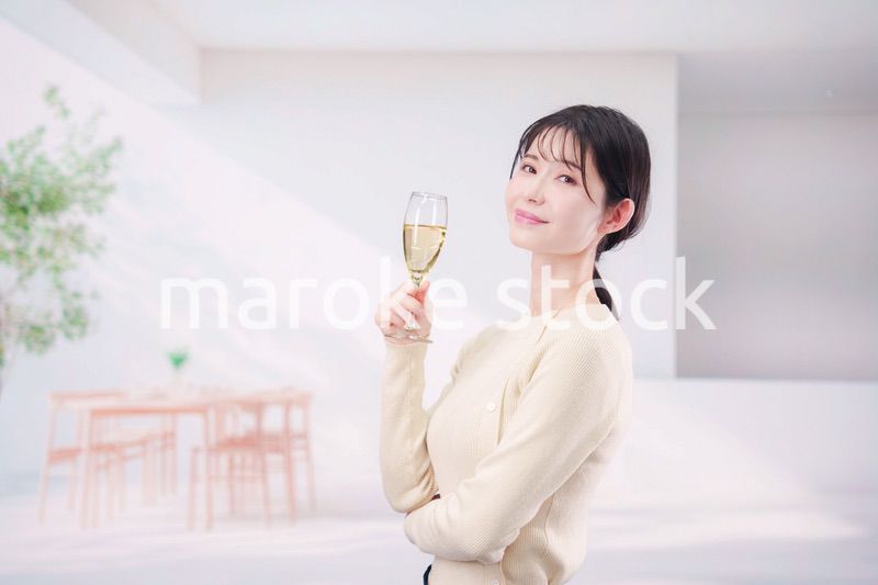 家でグラスワインを飲む若い女性