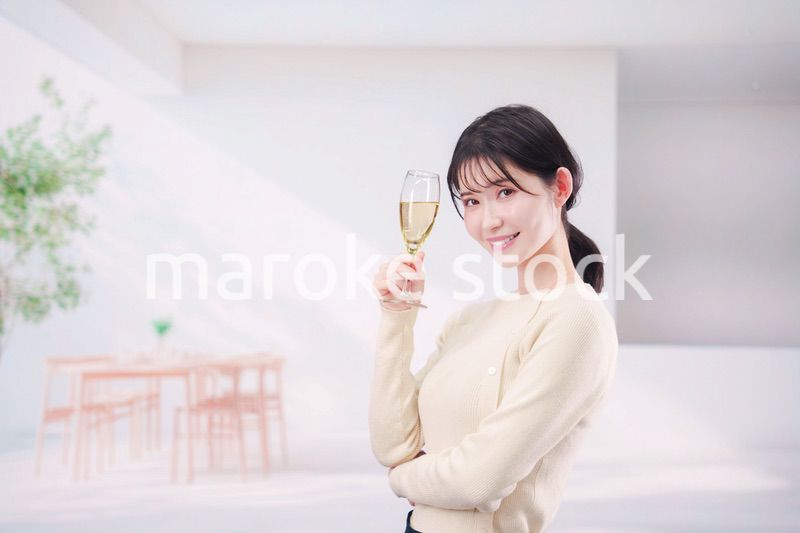 家でグラスワインを飲む若い女性