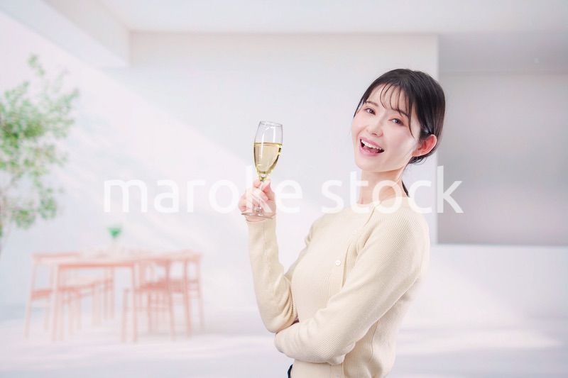 家でグラスワインを飲む若い女性