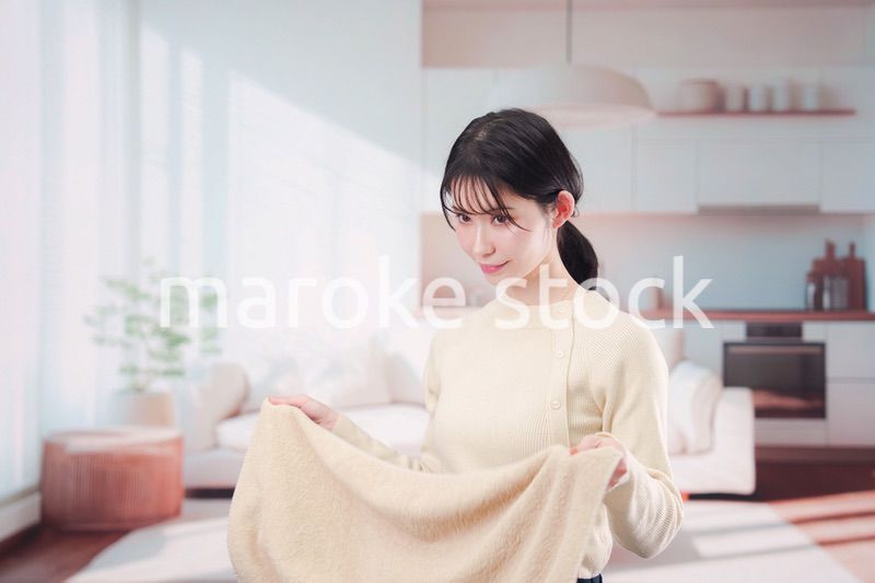 家で洗濯物をたたむ若い女性