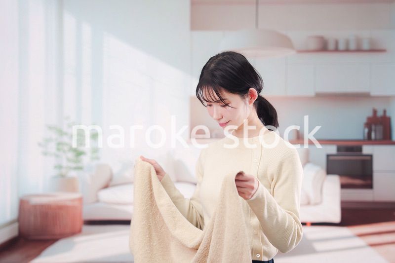 家で洗濯物をたたむ若い女性