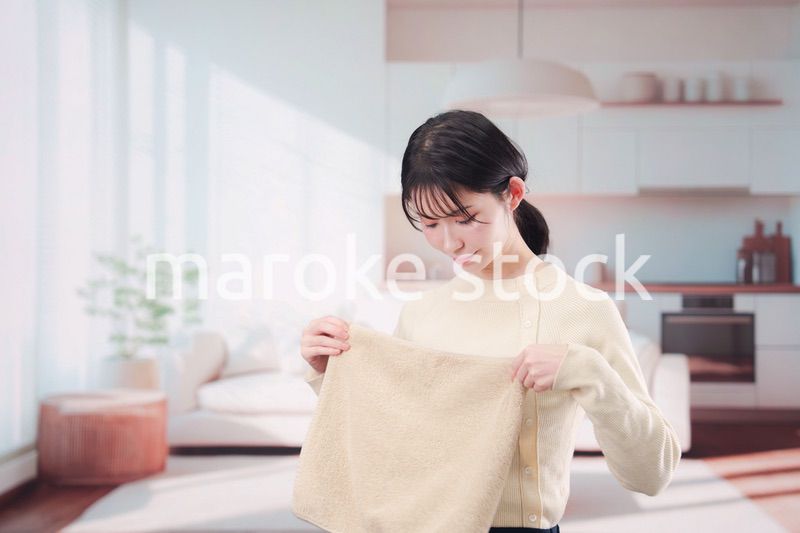 家で洗濯物をたたむ若い女性