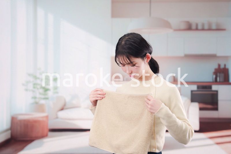 家で洗濯物をたたむ若い女性