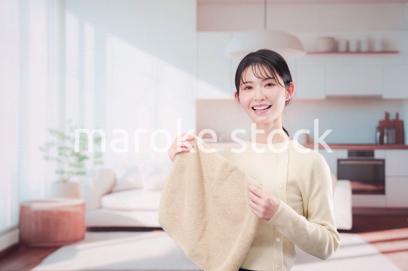 家で洗濯物をたたむ若い女性