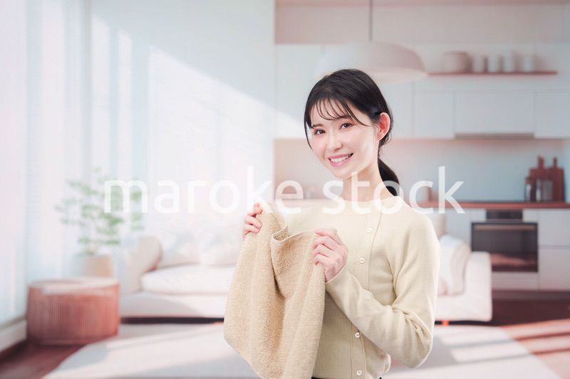 家で洗濯物をたたむ若い女性