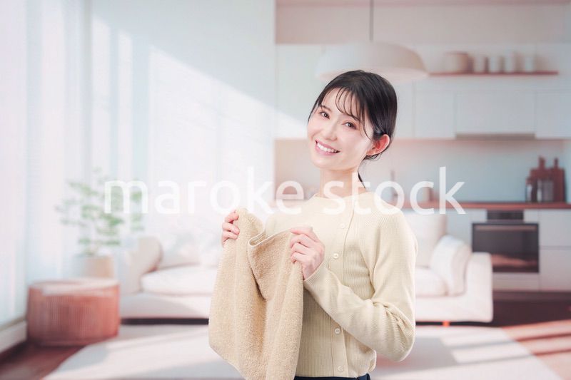 家で洗濯物をたたむ若い女性