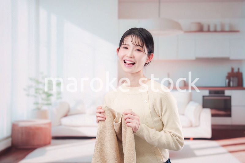 家で洗濯物をたたむ若い女性