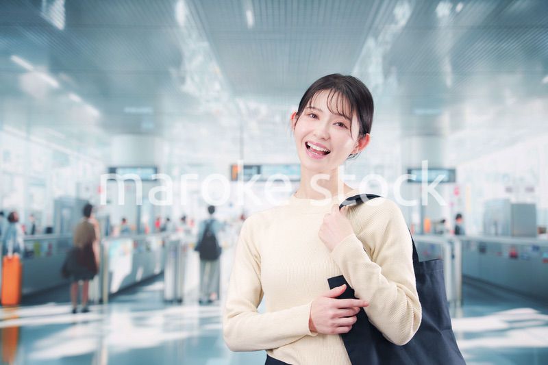 駅で笑顔で待ち合わせをする若い女性