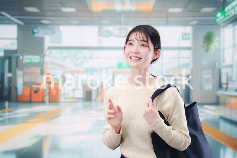 駅で笑顔で待ち合わせをする若い女性