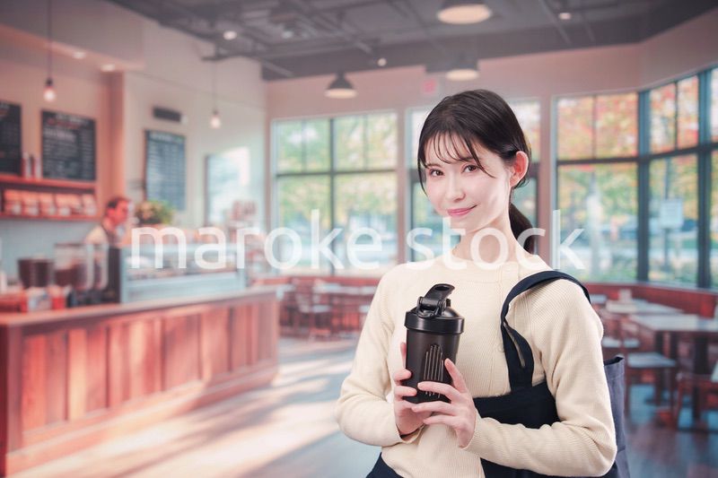 マイカップを持ってカフェに入る若い女性